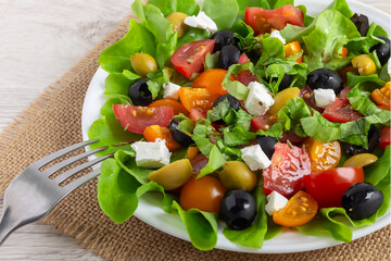 Fresh appetizing vegetable greek salad for healthy eating on a white plate.