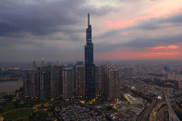 Fototapeta na wymiar Aerial urban colorful sunrise panorama with high rise building disappearing into the clouds, city center skyline and suburban sprawl