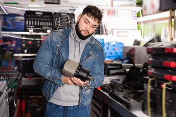 Positive cheerful smiling male is standing with new impact wrench in tools store