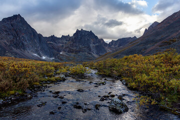Beautiful Dramatic View of Rugged Mountains and Peaceful Alpine River at Sunset in Canadian Nature. Taken near Grizzly Lake in Tombstone Territorial Park, Yukon, Canada.