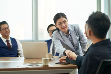 young asian businessman and businesswoman shaking hands during meeting