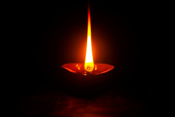 Diwali Diya in black. Deepam oil lamp. Flame in dark. a light powered by coconut oil.