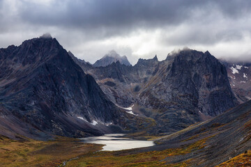 Beautiful View of Dramatic Mountains and Scenic Alpine Lake during Fall in Canadian Nature. Aerial Shot. Taken in Tombstone Territorial Park, Yukon, Canada.