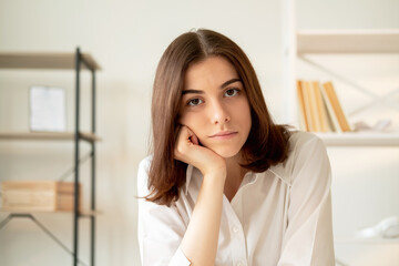 Fototapeta premium Boring lesson. Online training. Videochat conference. Uninterested woman leaning head on hand looking at camera home workplace interior background.