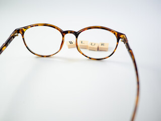 Glasses and a block of letters that read BLUR, Clear vision on eyeglass lenses