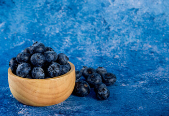 Blueberry in a bowl on blue background, for healthy eating and nutrition.