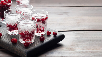 Stacks of vodka and cranberries on a wooden stand and background. Copy of the space. Bar alcoholic beverage tincture. - obrazy, fototapety, plakaty