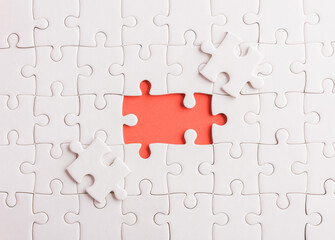 Fototapeta premium Top view flat lay of paper plain white jigsaw puzzle game texture last pieces for solve and place, studio shot on a red background, quiz calculation concept