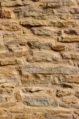 Full frame abstract texture background of a shabby chic antique tan color rugged stone wall with natural stones and thick cement mortar