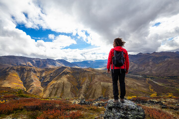 Woman Standing and Looking at Mountain Range on a Cloudy Fall Day in Canadian Nature. Taken in Tombstone Territorial Park, Yukon, Canada.