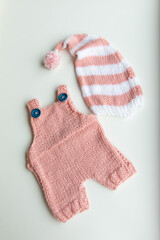 Various colors and types of cotton clothing, knitted newborn clothes and newborn hats on a white background.