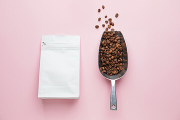 Scoop with coffee beans and bag on color background
