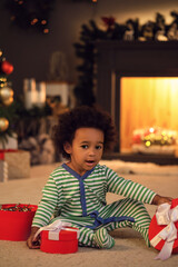 Fototapeta na wymiar Cute African-American baby girl with gift at home on Christmas eve