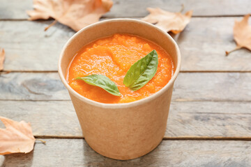Tasty pumpkin cream soup in cup on table