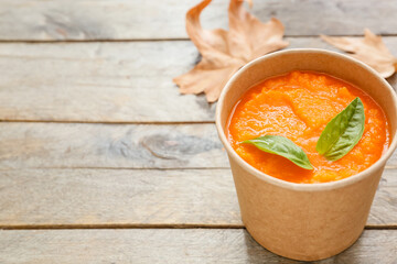 Tasty pumpkin cream soup in cup on table