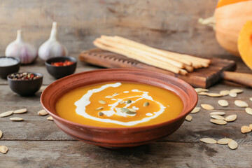 Tasty pumpkin cream soup in bowl on table