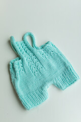 Various colors and types of cotton clothing, knitted newborn clothes and newborn hats on a white background.