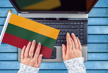 woman hands and flag of Lithuania on computer, laptop keyboard 