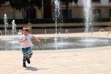 A young boy having fun by a fountain on holiday