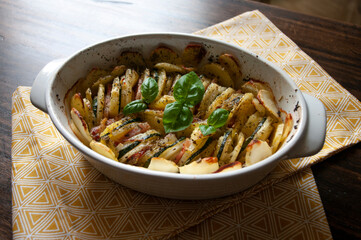 Hearty potato gratin bacon and zucchini,freshly served from the oven on a wooden table.Casserole dish recepie,vessel. Spanish food.