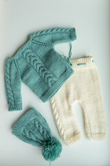 Various colors and types of cotton clothing, knitted newborn clothes and newborn hats on a white background.