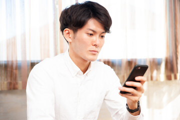 Obraz premium 部屋でスマホを使う男性 