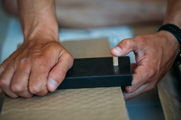 Shallow focus images of man assembling furniture at home using a  screwdriver.