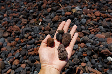 Natural pumice stone or of volcanic rocks in hand on Perissa beach, Santorini, Greece.