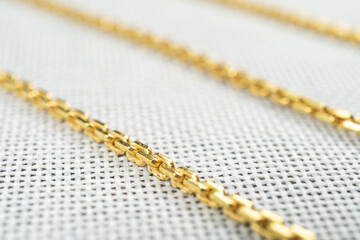 Gold chain necklaces over white sack background.