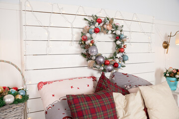 Obraz premium Christmas wreath made of fir branches, cones and Christmas toys on the wall.warm cozy modern design of the bedroom in bright colors decorated with Traditional hristmas wreath and decorative elements