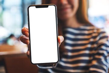 Mockup image of a beautiful asian woman holding and showing a mobile phone with blank white screen