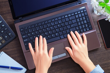 Aerial view of woman typing on laptop. Placed on wooden desk