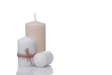 one white candle in jute rope, one white candle lying on its side and one beige vanilla candle isolated on a white background.