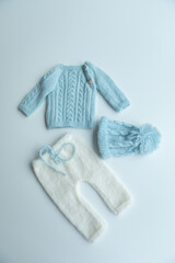 Various colors and types of cotton clothing, knitted newborn clothes and newborn hats on a white background.