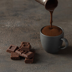 Hot chocolate poured from pot into ceramic mugp. Winter times drink concept.
