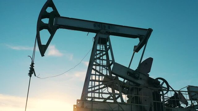 Zooming in shot of oil pumpjack at oil field