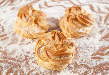 Freshly baked eclairs with cream on the table.