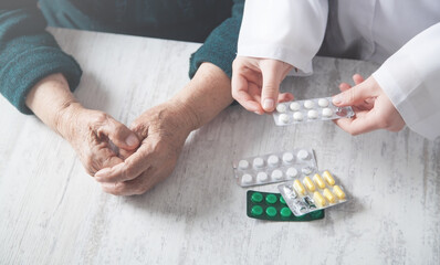 Doctor giving pills to elderly woman.