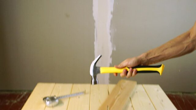 Hammer a nail into the Board.A construction worker throws and catches a hammer in slow motion.The carpenter improves his skill with the tool. The hammer tumbles in the air in flight.