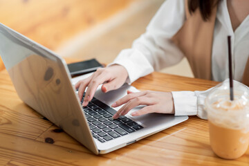 Close up. Woman sitting at desk and working at laptop computer.