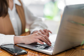 Close up. Woman sitting at desk and working at laptop computer.