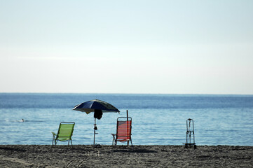 Abandoned beach chairs and an umbrella on a beach in Spain. A deserted place.