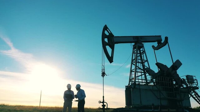 Business negotiations at oil field on oil pumpjack background