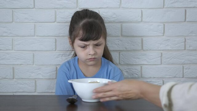 Dislike oatmeal. Mischievous little girl refuses morning porridge.