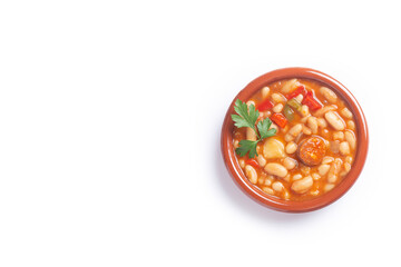 Traditional Spanish dish of beans stew with chorizo and potatoes, isolated on white background. With copy space.