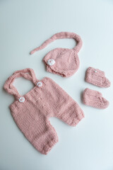 Various colors and types of cotton clothing, knitted newborn clothes and newborn hats on a white background.