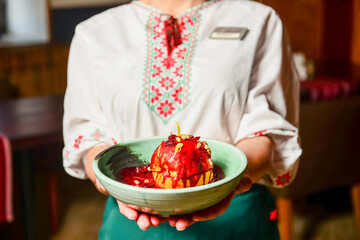 Delicious sweet baked apple with raisin, sugar sauce and walnuts served in a bowl over traditional red table cloth.