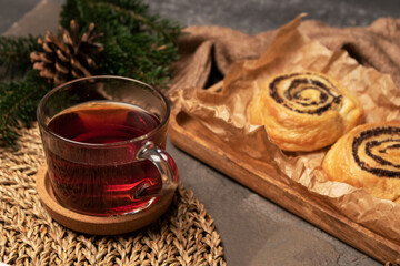 A mug of tea, buns with poppy seeds, a spruce branch on the table. Side view.