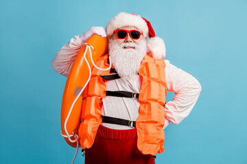 Photo of retired old man grey beard yacht tour liner captain hold inflatable circle prepare long swim summer wear life vest santa x-mas costume sunglass cap isolated blue color background