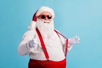 Fototapeta na wymiar Portrait of his he nice attractive cheerful confident flirty thick white-haired Santa pointing at you date invite pulling suspender isolated bright vivid shine vibrant blue color background